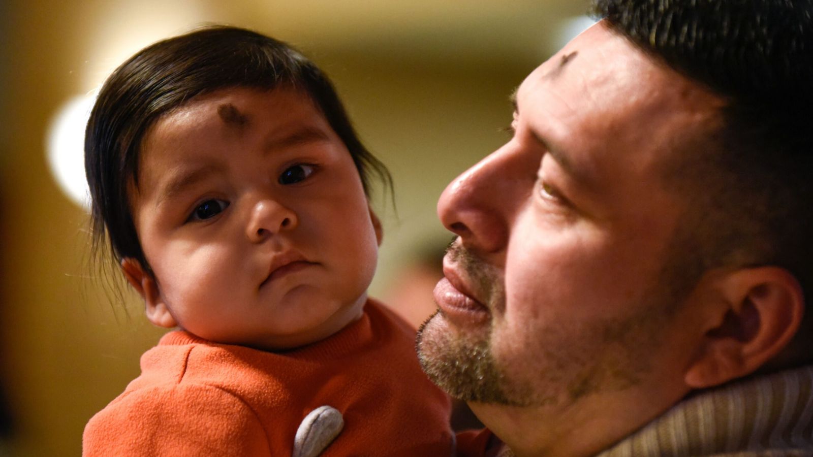 Juan Flores, right, holds his 8-month old child after his family received Ash during Ash Wednesday at Our Lady of Perpetual Help Parish in Dallas, Feb. 26, 2020. Ben Torres/Special Contributor